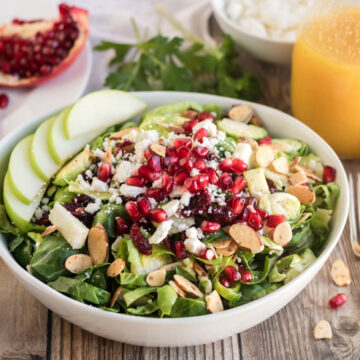 Brussel Sprout Salad with Pomegranate- a picture of a brussel sprout salad with almonds, apples, cranberries, feta and pomegranate on it.
