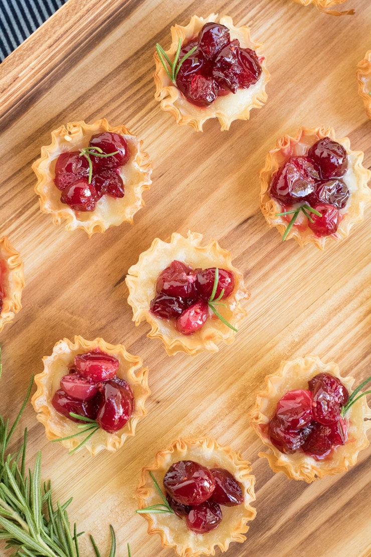 Cranberry Brie Bites: A picture of a phyllo shell filled with brie and cranberries garnished with a sprig of rosemary. 