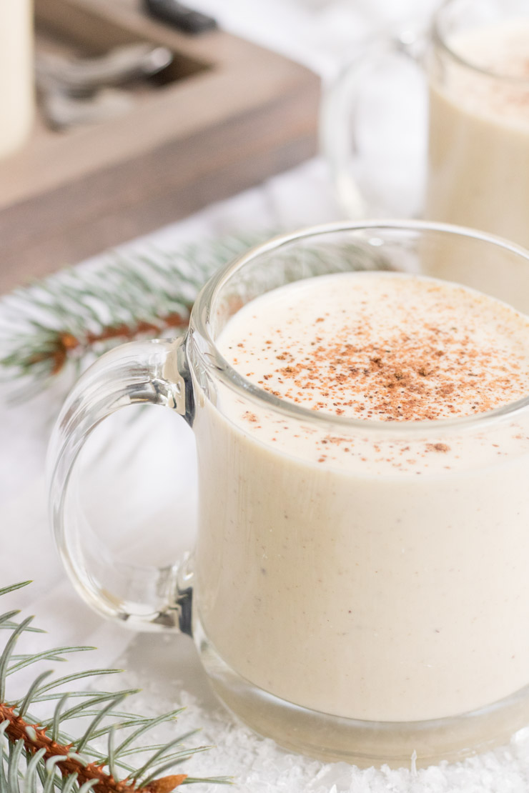 Egg Nog Recipe, a glass of homemade egg nog in a clear mug with nutmeg on top. 