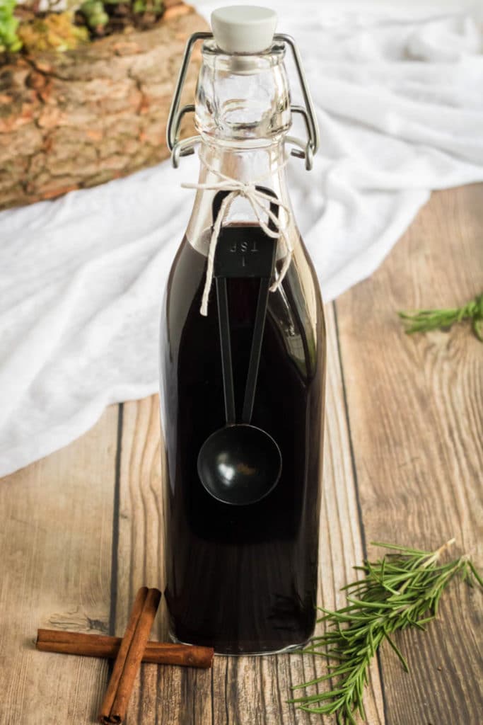 Elderberry Syrup Recipe: A swing top bottle of Elderberry Syrup with a teaspoon tied around the neck. 