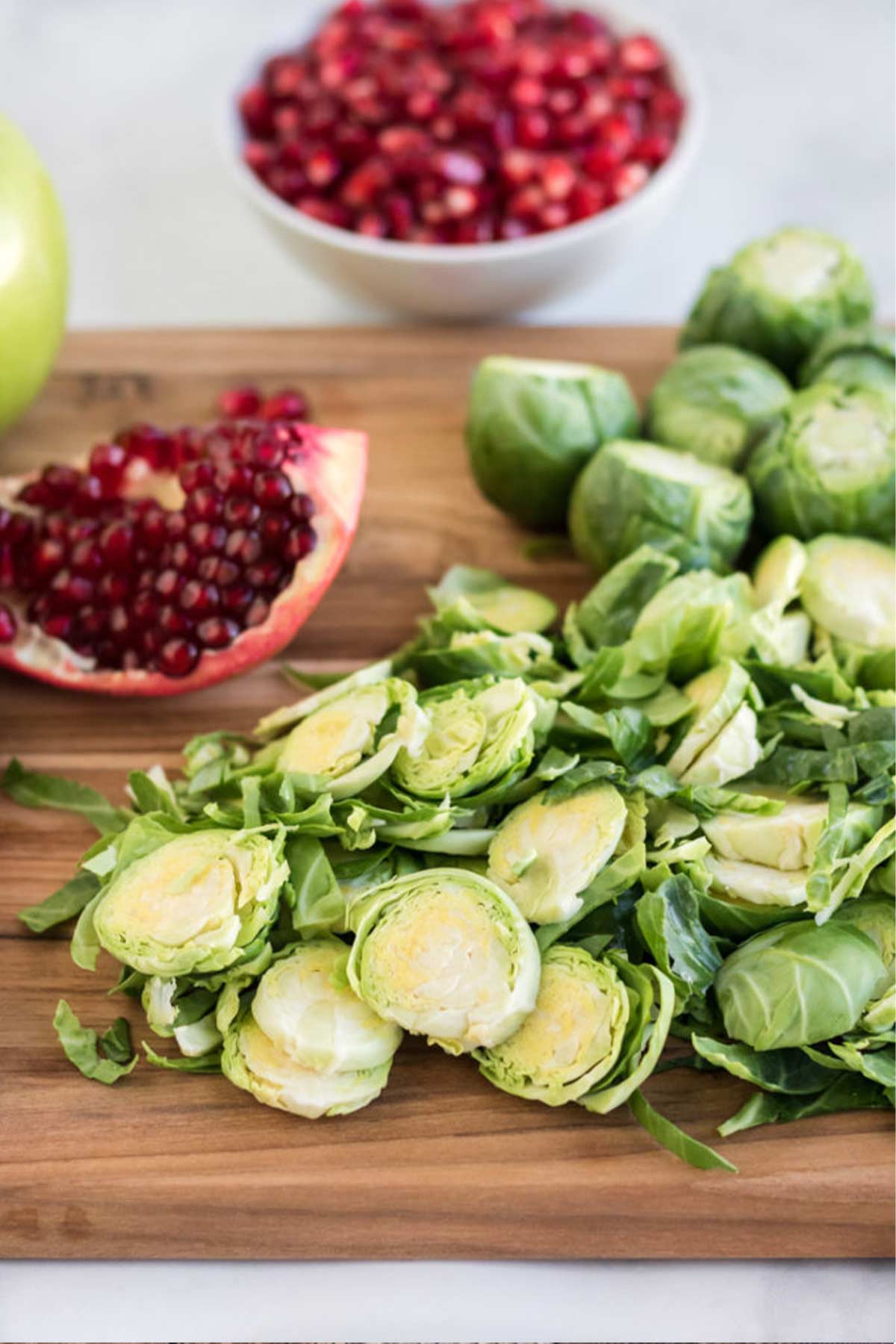 Ingredients to make a salad with brussel sprouts on a cutting board.