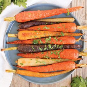 Plate of whole roasted rainbow carrots ready to eat.