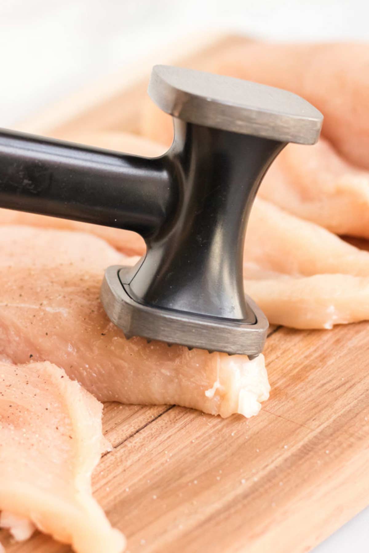 Pounding the chicken breast to make Champagne chicken with mushrooms.