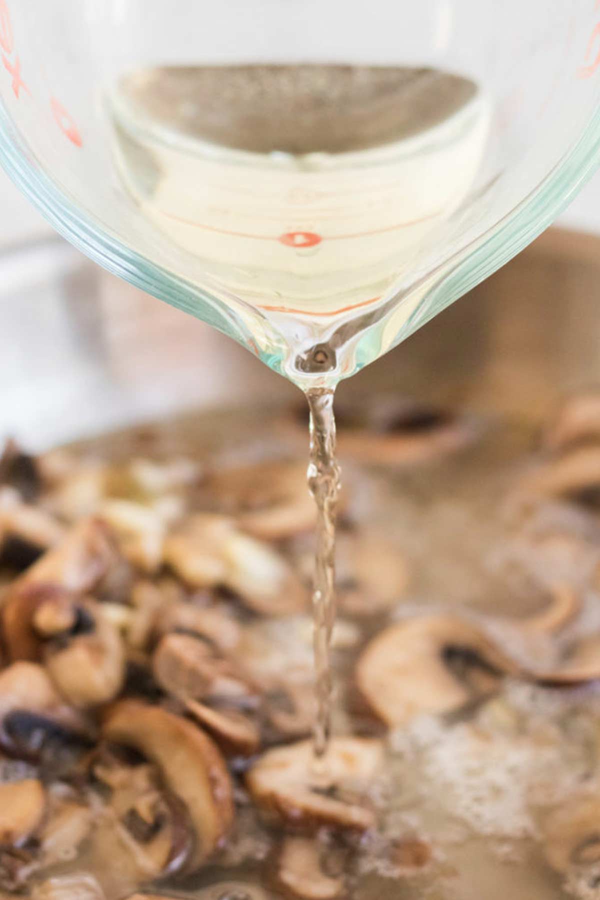 Pouring wine into the pan of mushrooms.