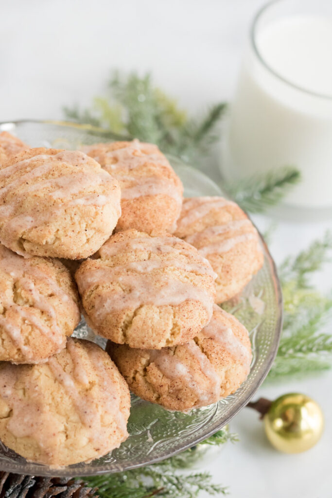 Egg Nog Cookies on a platter with a glass of milk behind them. 