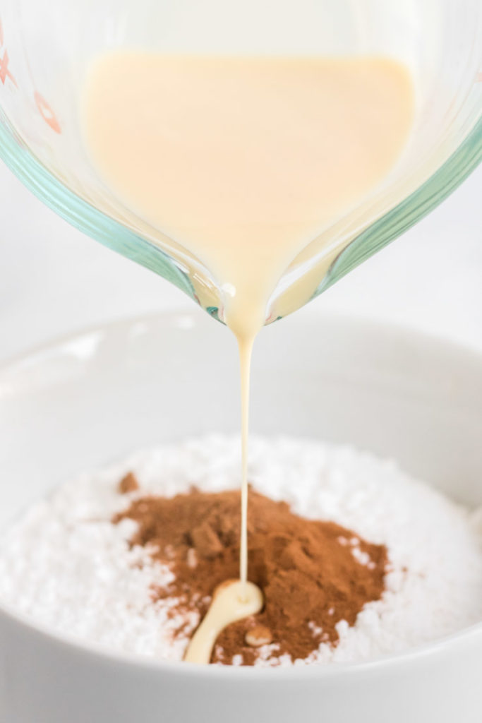 Egg Nog Cookies- egg nog being poured into a bowl to make egg nog glaze