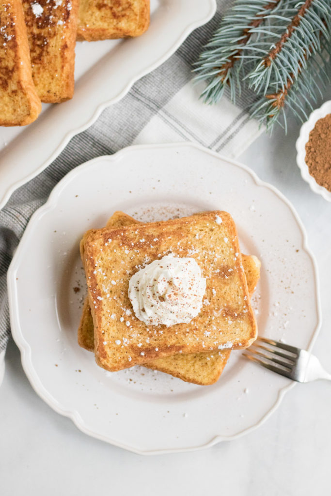 Overhead image of egg nog french toast on a plate with whipped cream