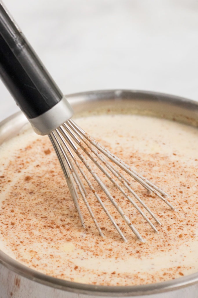 Egg nog being whiske in a small saucepan.