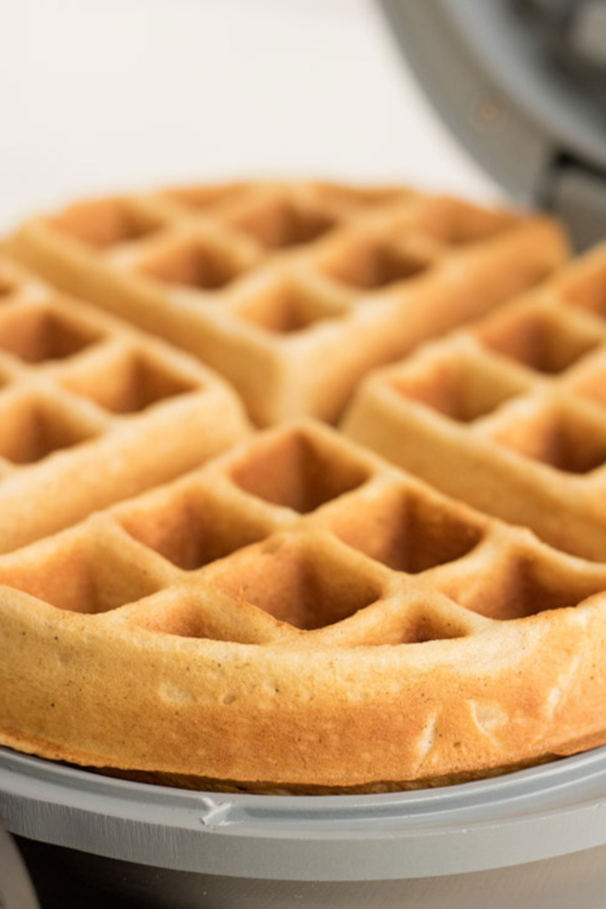 Eggnog waffle being cooked in a waffle iron. 