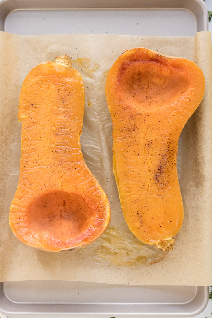 Two roasted butternut squash halves, face up with a little bit of salt and pepper on them.