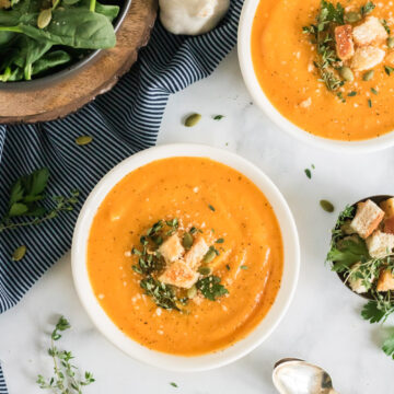 A bowl of butternut squash soup with croutons, pumpkin seeds and thyme