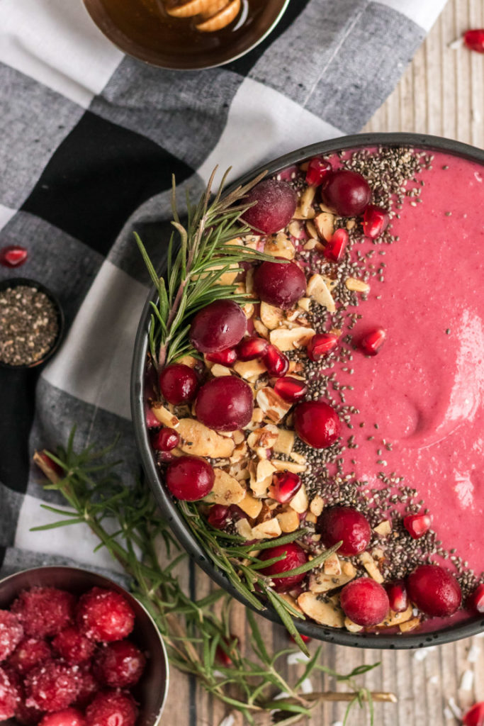 Half bowl image of a cranberry smoothie bowl with lots of garnishes. 