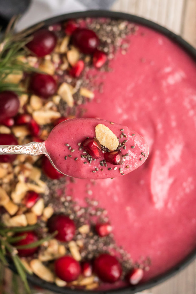 Cranberry smoothie bowl images with a spoon closeup over the bowl