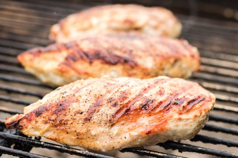 Chicken breasts cooking on a charcoal grill