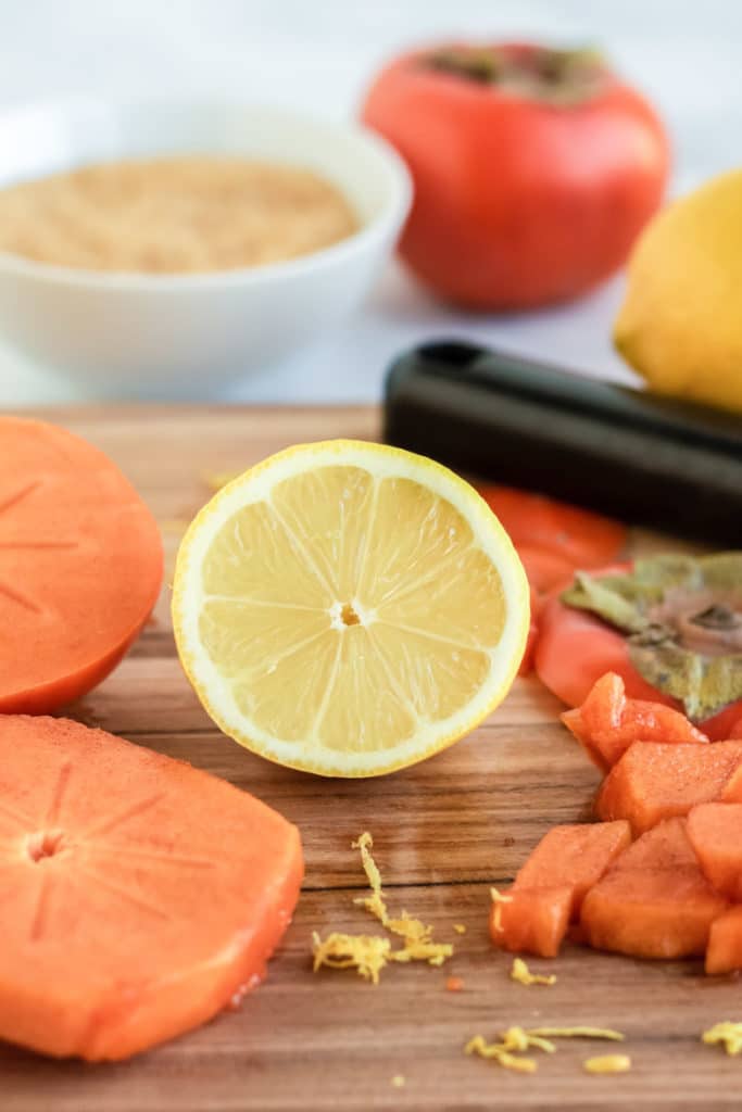 Ingredients for persimmon butter. Fresh persimmon slices and lemon on a cutting board. 