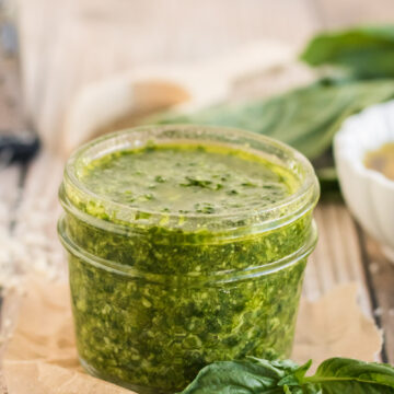 nut free basil pesto in a small jar with basil in the background