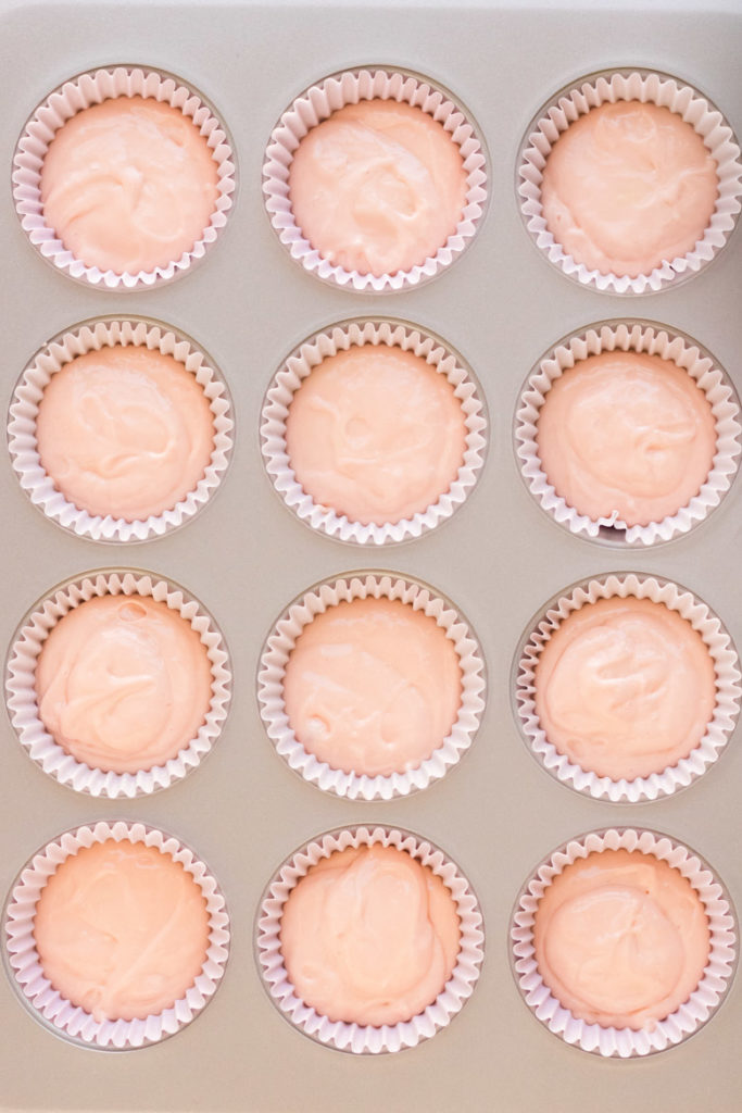 Raw pink champagne cupcake batter in a muffin tin with light pink liners. 