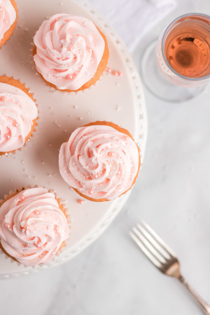 Overhead shot of pink champagne cupcakes on a white cake platter. 