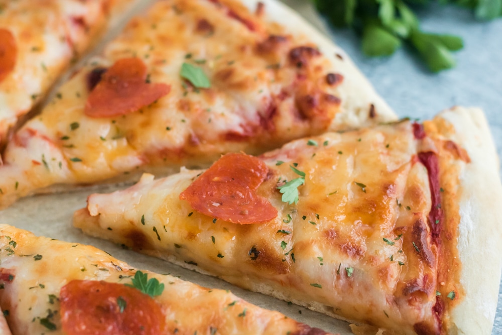 A close-up image of a slice of pizza with a heart shaped pepperoni on it. 