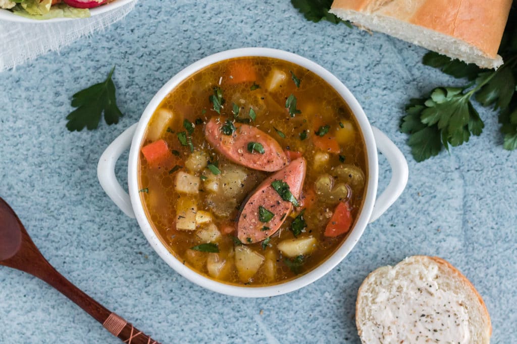 An overhead image of Bavarian Potato Soup with two diagnal sliced sausages on top
