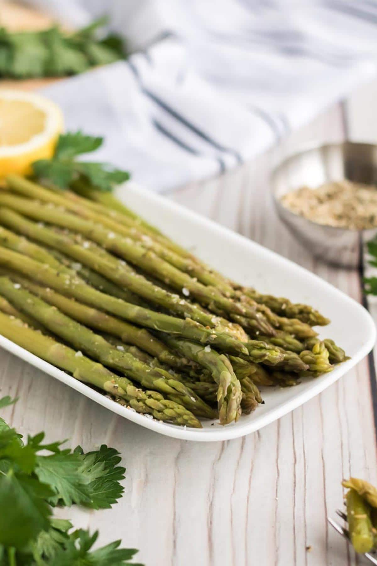 Asparagus cooked in the instant pot is served on a white plate.