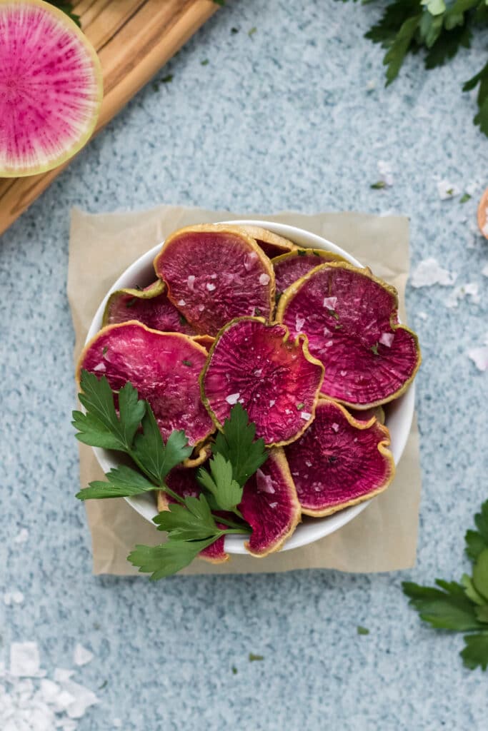 Roasted Watermelon Radish chips in a bowl with a blue background