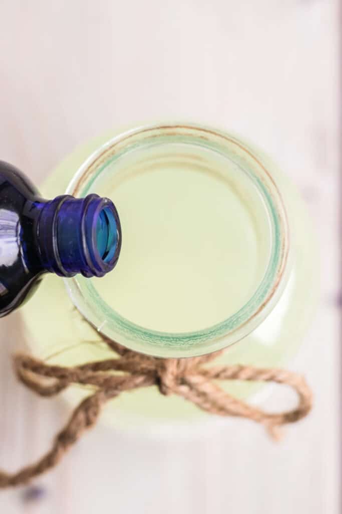 Lavender essential oil being poured into a pitcher of lemonade