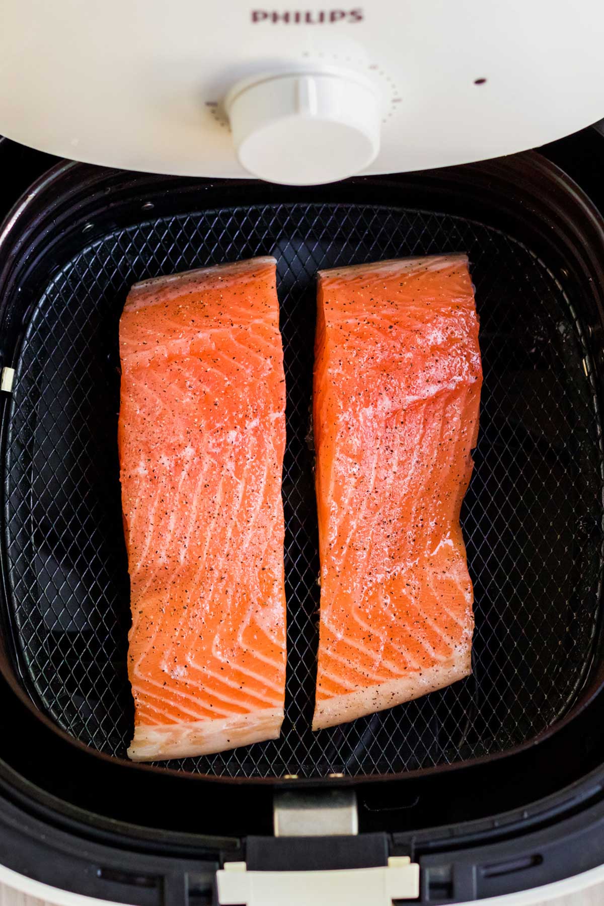 Salmon fillets are placed on the rack in the air fryer.