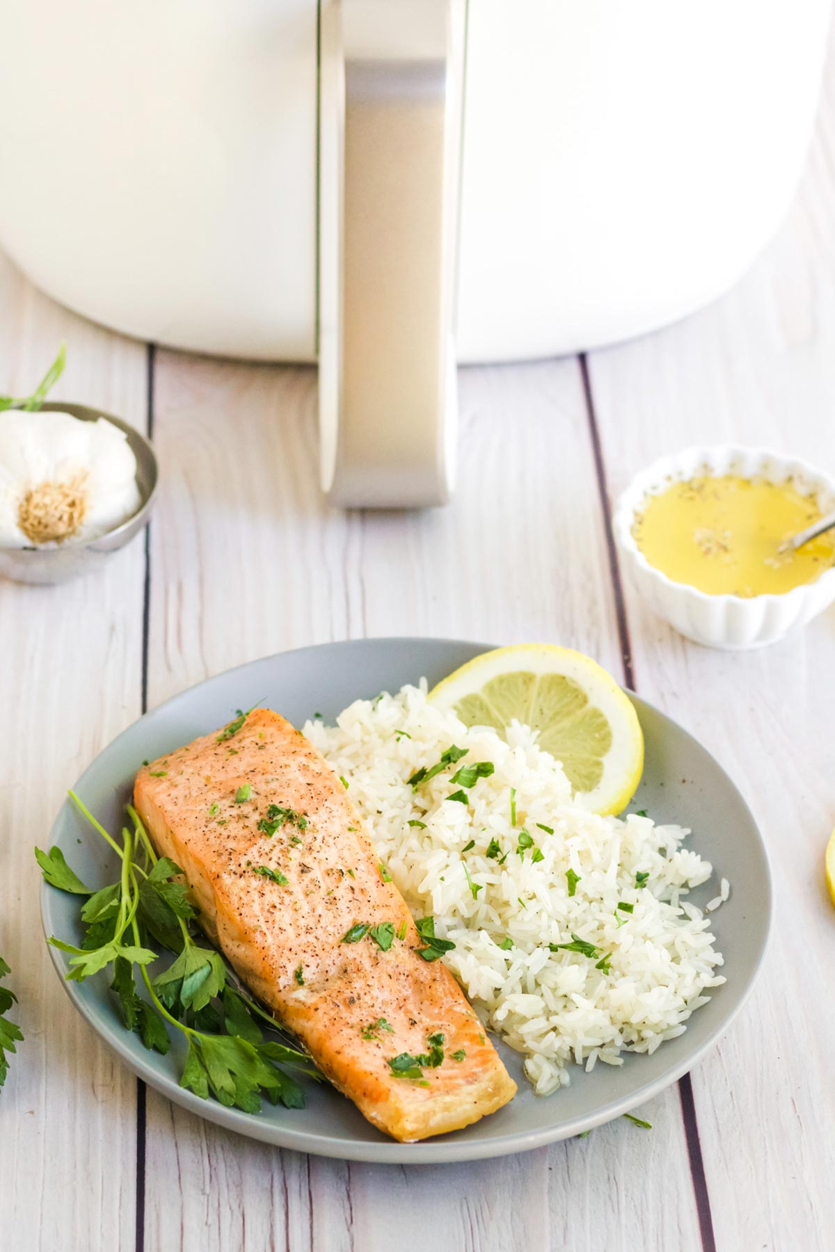 Air fried salmon served up with rice and lemon slices with fresh parsley.
