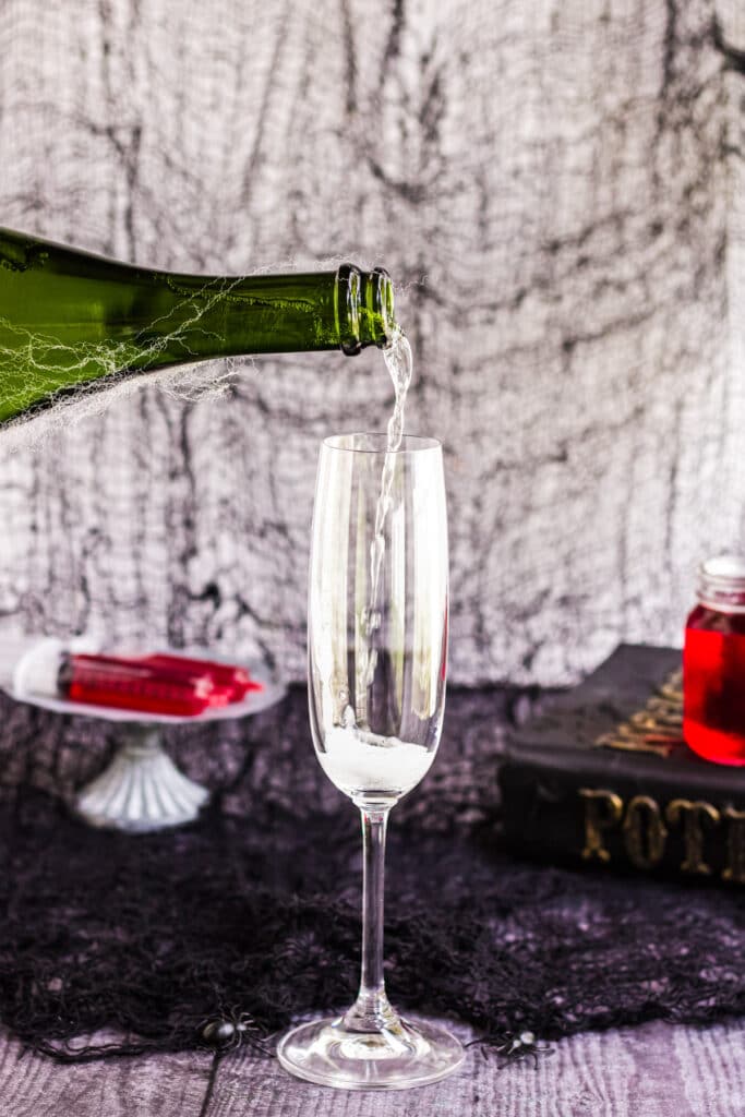 Sparkling wine being poured into a glass to make a Halloween Mimosa. 