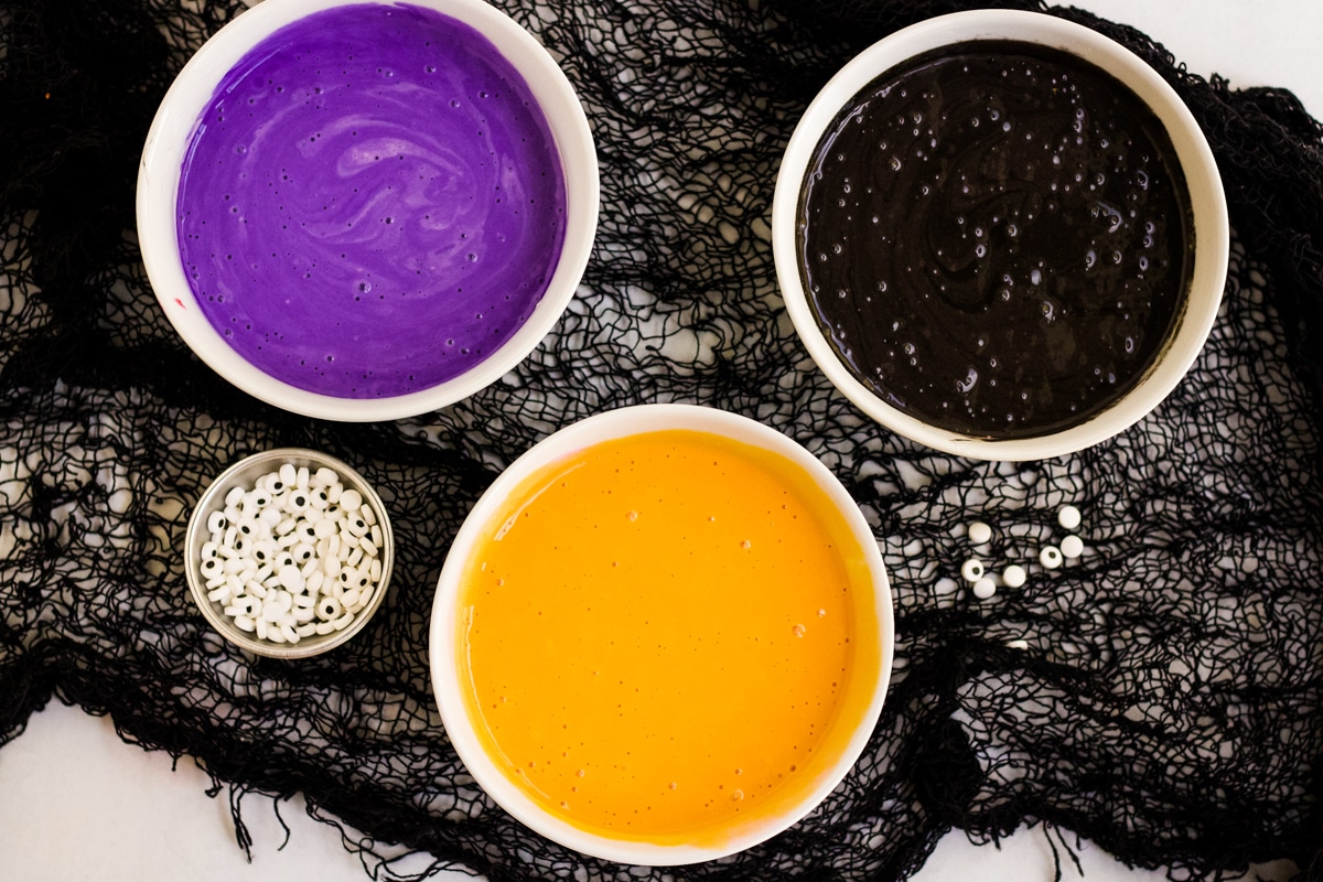 Three bowls of colored pancake batter to make Halloween Pancakes.