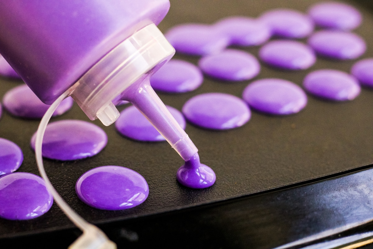Purple pancake batter being squeezed onto a griddle to make Halloween pancakes. 
