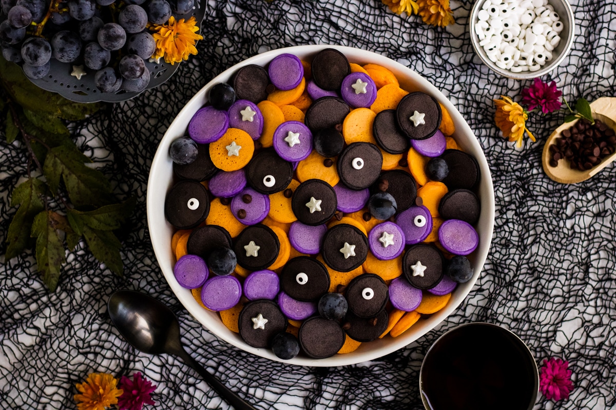 A bowl full of black, orange and purple mini pancake cereal.