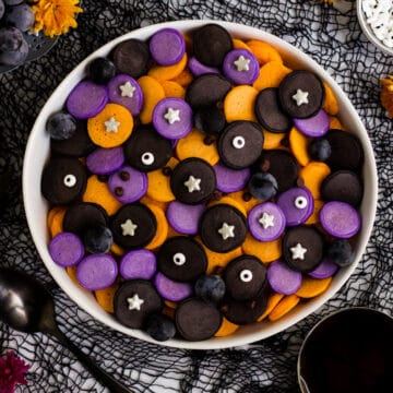 A bowl of purple, orange and black mini Halloween pancakes with candy eyes and stars.