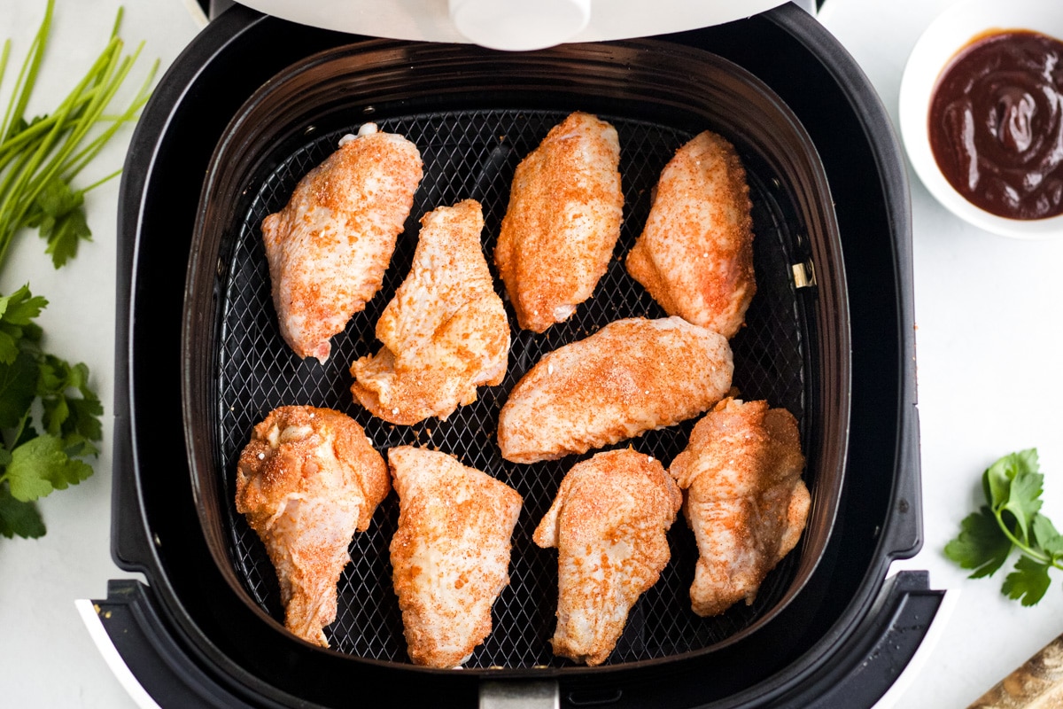 Chicken wings laid in the basket of the air fryer.
