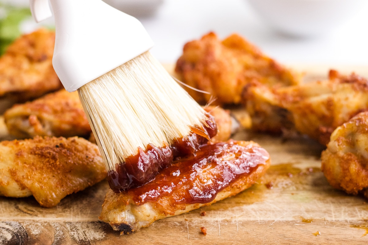 Pastry brush adding barbecue sauce to the wings.