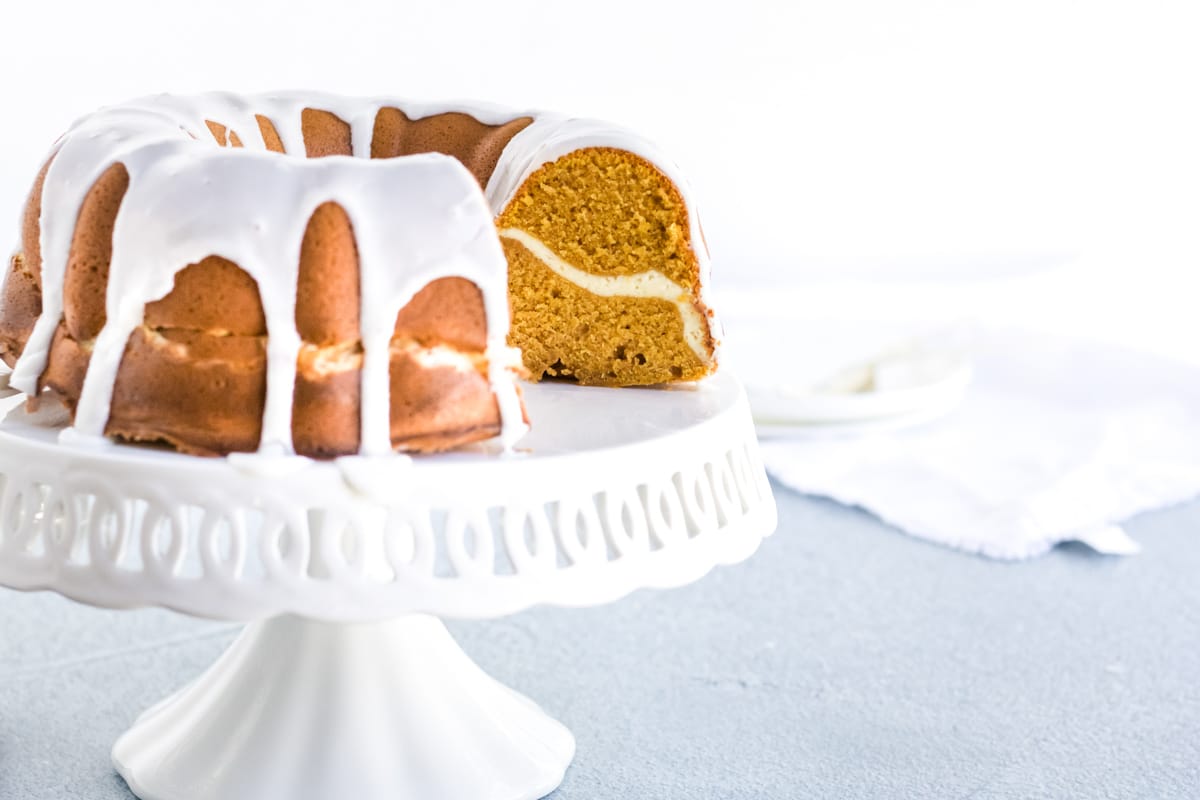 A cream cheese stuffed pumpkin pound cake with a glaze dripping off the sides. 