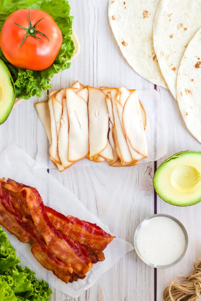 Ingredients to make a turkey bacon BLT wrap.