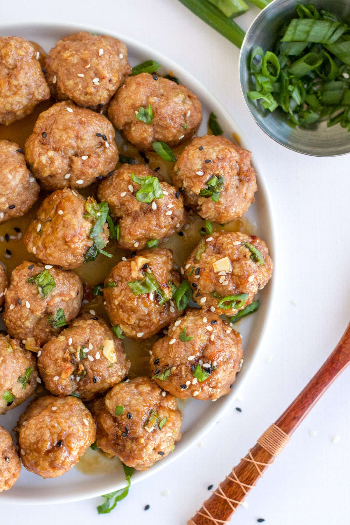 white plate of turkey meatballs topped with scallions and sesame seeds
