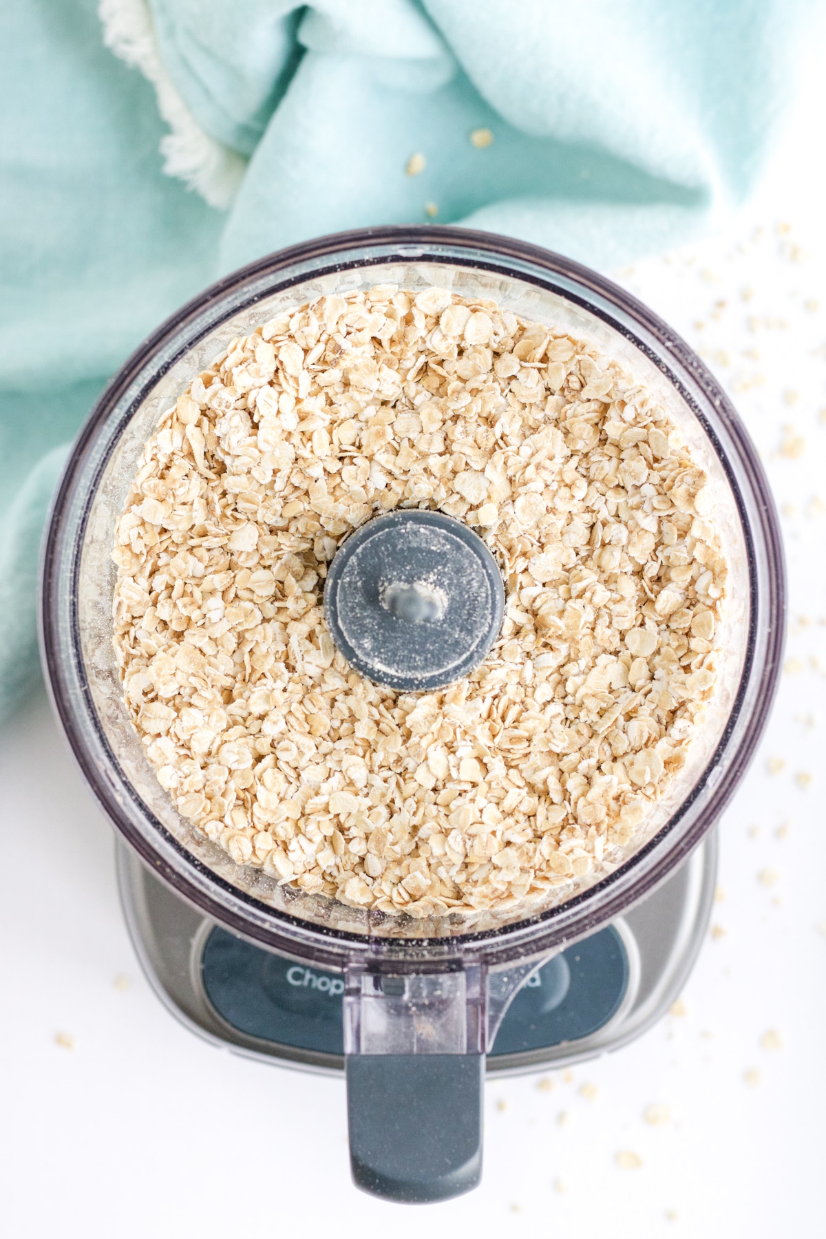 An overhead image of oats inside a food processor in preparation to make oat flour at home. 