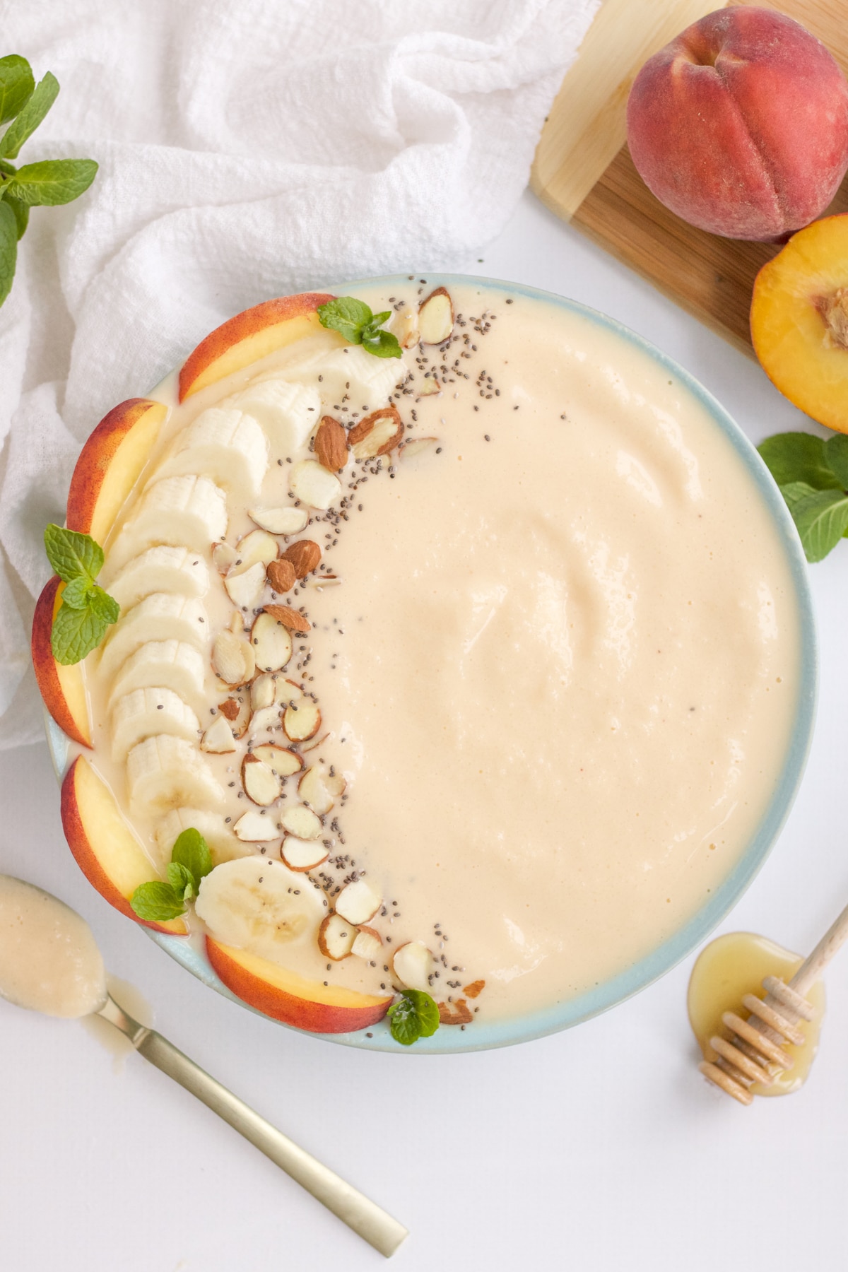 peach smoothie bowl with fresh fruit and nut toppings