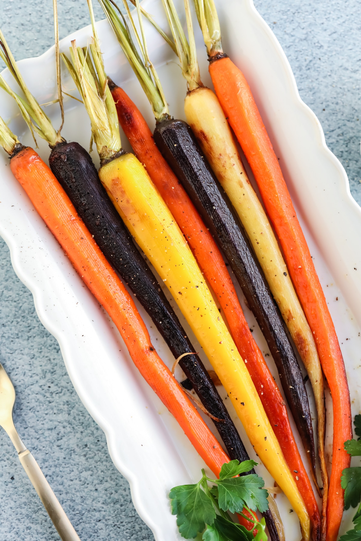 Overhead image of roasted rainbow carrots on a white platter. 