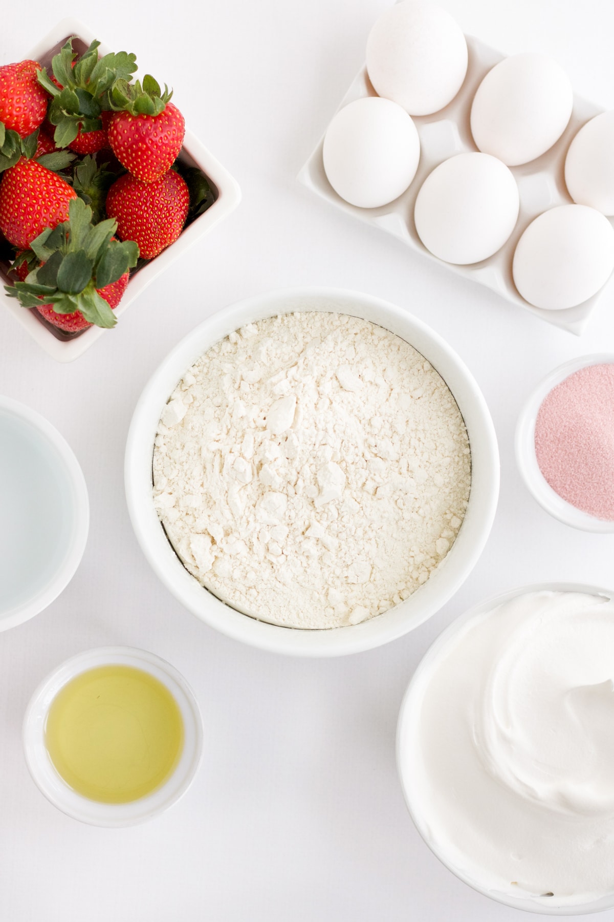 several white containers with different ingredients for a cake