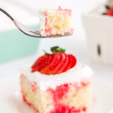 fork taking a bite from a slice of strawberry poke cake