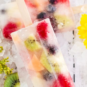 two popsicles with fruit on crushed ice