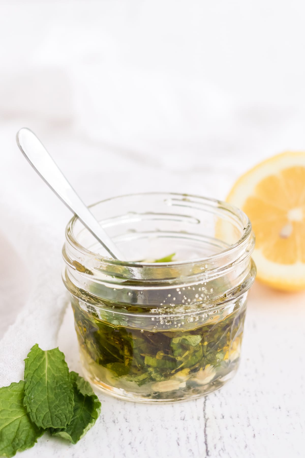 small glass jar and spoon with herb vinaigrette. 
