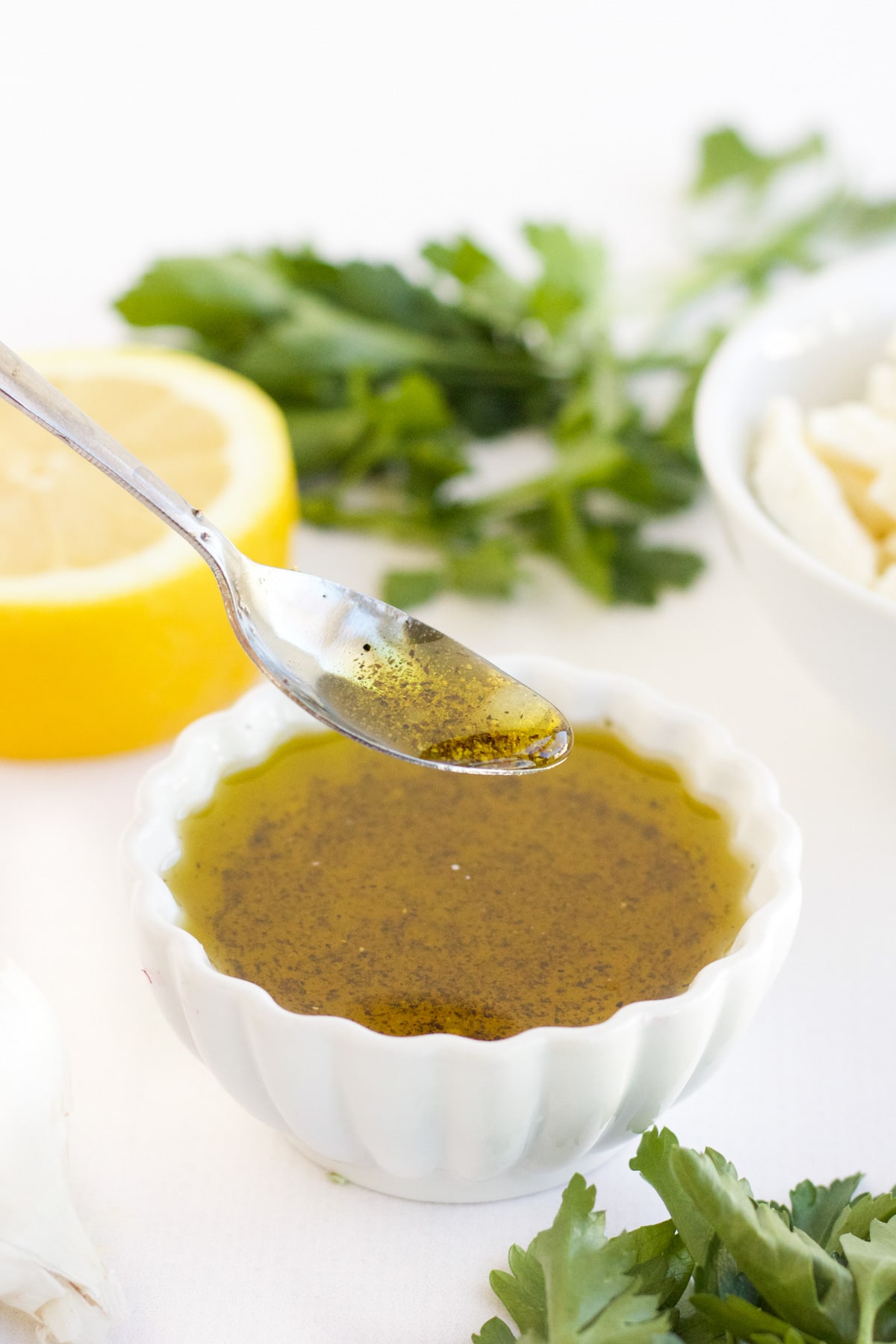 The dressing in a small white bowl with a silver spoon. 