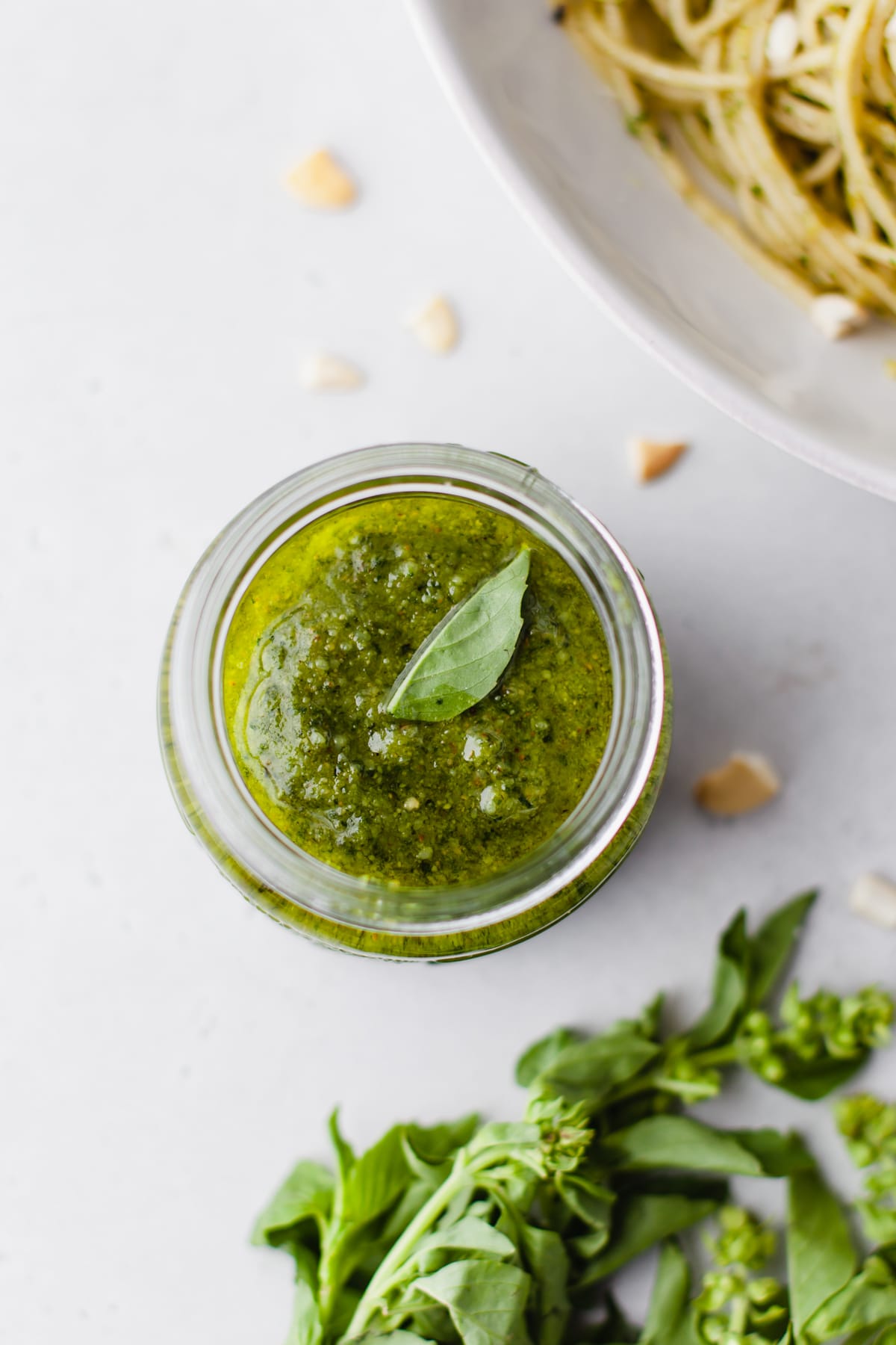 An overhead image of homemade cashew pesto in a jar with fresh basil on top. 