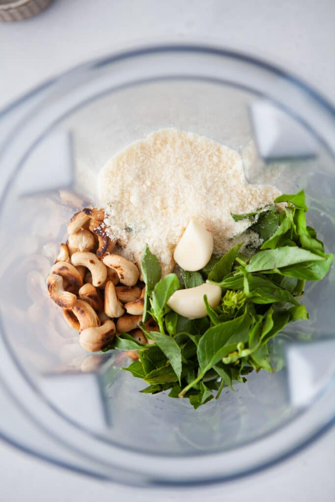 Toasted cashews, basil, fresh parmesan and garlic in a blender in preparation of making Copycat Trader Joe's Black Truffle Pesto Sauce 