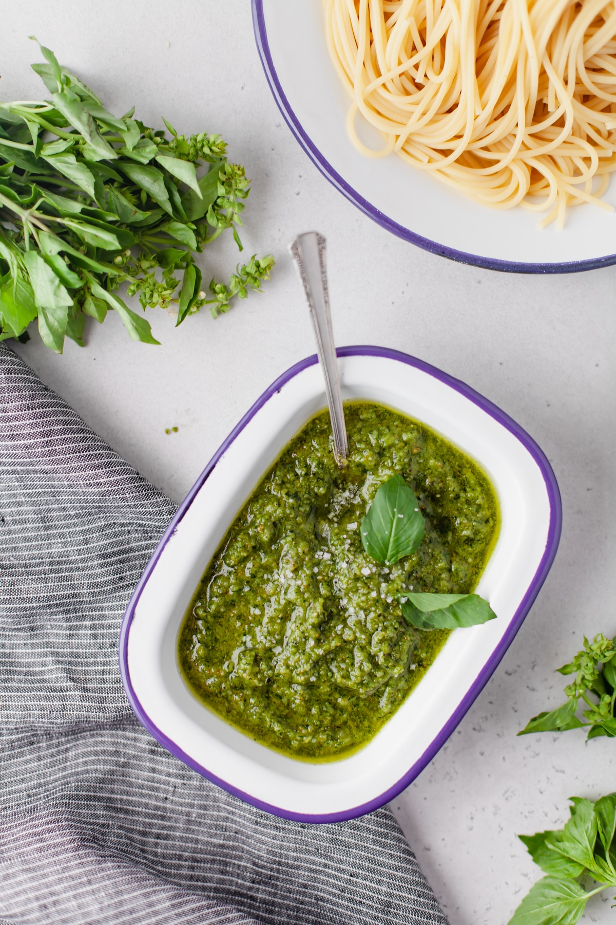 An overhead image of homemade cashew pesto sauce with a dish of noodles in the background. 